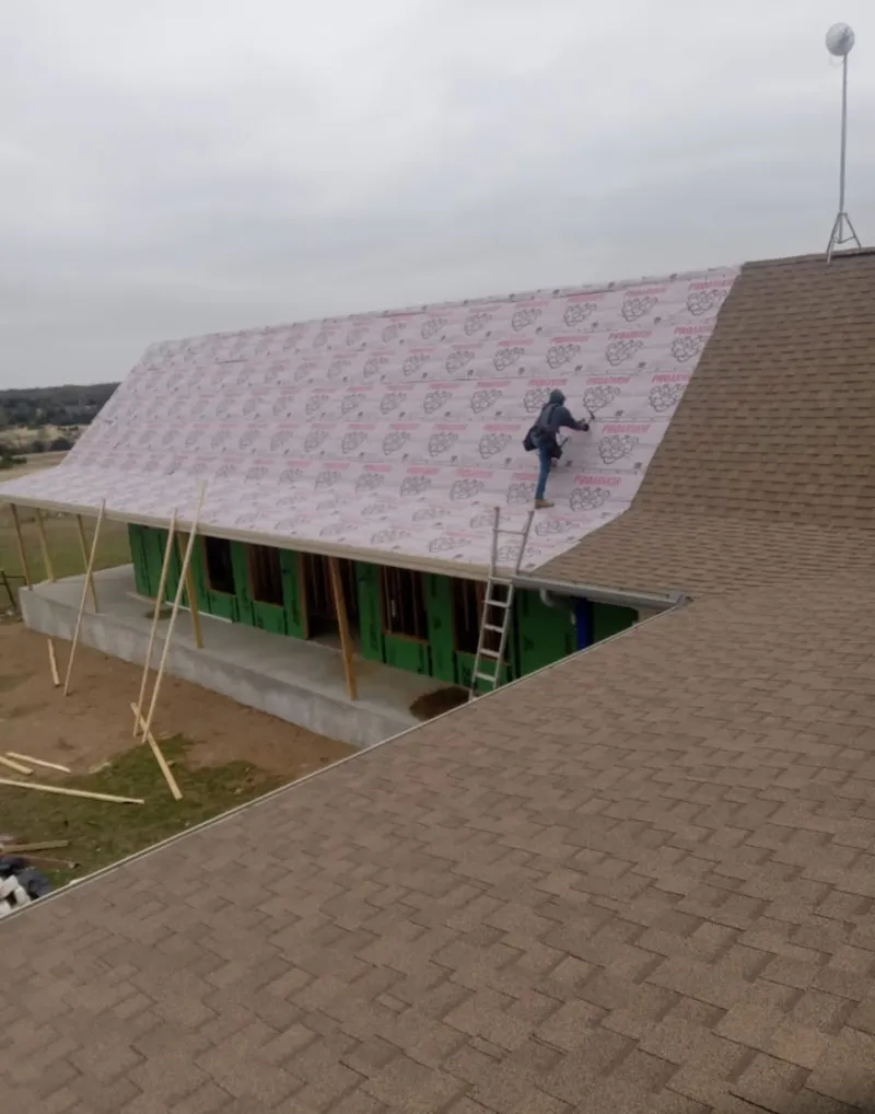 Worker preparing underlayment for a metal roof installation in Cary